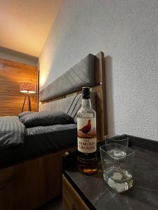 a bottle of alcohol sitting on a table next to a bed at Cozy Central Corner in Gjakove