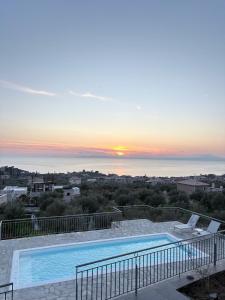 a swimming pool with a sunset in the background at Thalassori Villas in Agios Nikolaos
