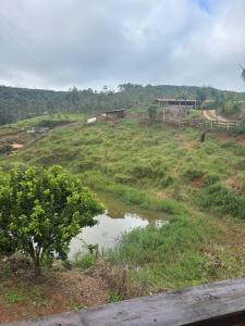 a grassy hill with a pond in a field at Chalé do Vicente in Ouro Preto
