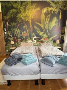 two beds in a room with a tropical wallpaper at Maison François in Oostkamp