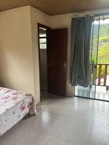 a bedroom with a bed and a sliding glass door at Chalé do Vicente in Ouro Preto