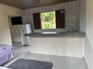 a kitchen with a counter with a refrigerator and a window at Chalé do Vicente in Ouro Preto
