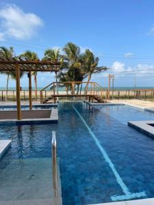 a large swimming pool with palm trees and the ocean at House Paraíso Flecheiras in Trairi