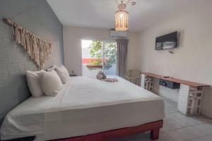 a bedroom with a large bed with a desk and a window at Ahava Hotel in Playa del Carmen