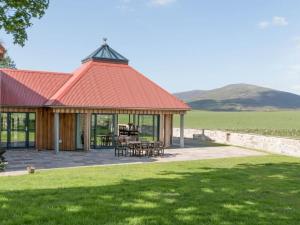 a pavilion with a red roof in a field at Millbank in Ballindalloch