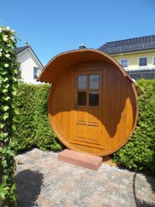a circular wooden building with a door in a yard at Ferienhaus am Eikboom - DHH1 mit Fasssauna in Ostseebad Karlshagen