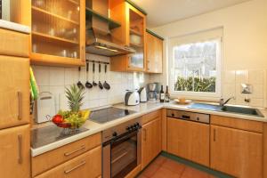 a kitchen with wooden cabinets and a bowl of fruit on the counter at Ferienhaus am Eikboom - DHH1 mit Fasssauna in Ostseebad Karlshagen