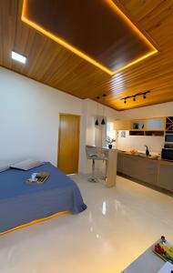 a bedroom with a bed and a desk and a kitchen at Suíte dos Sonhos-Climatizada,Hidromassagem,Garagem in Piratuba
