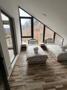 two beds in a room with large windows at Guest House Ropojan in Vusanje +12 photos