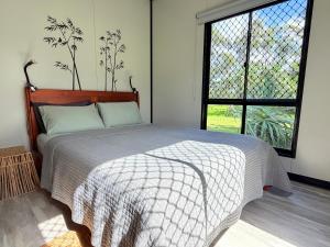 a bedroom with a bed and a large window at Feng Shui Sugarcane Cabin in Proserpine