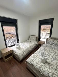 two beds in a room with two windows at Guest House Ropojan in Vusanje