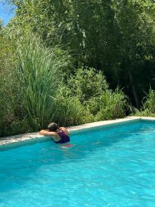 a woman is laying in a swimming pool at Cabañas Amo Río - Delta in Tigre +49 photos