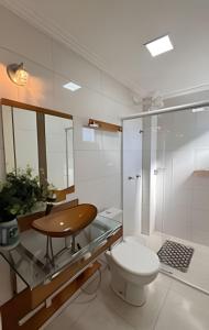 a bathroom with a toilet and a wooden table at Apto Antúrios|3Q. Sacada c/Churrasqueira in Piratuba +31 photos