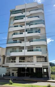 a tall white building with a sign on it at Apto Antúrios|3Q. Sacada c/Churrasqueira in Piratuba