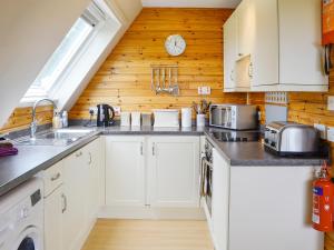 a kitchen with white cabinets and a wooden wall at Glenlivet View in Auchnastank