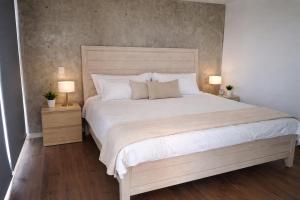 a bedroom with a large white bed with two lamps at Garden views in Juriquilla