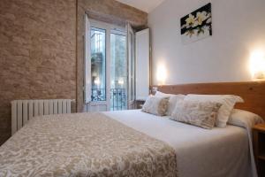 a bedroom with a white bed with pillows and a window at Hostal Anosa Casa in Santiago de Compostela