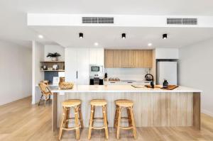 a kitchen with a large island with bar stools at THE COSMOPOLITAN COTTON TREE Unit 10207 Cotton Tree in Maroochydore