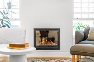 a fireplace in a living room with a chair and a table at Eastside Oasis - Heart of Norwood with Poolside Garden in Norwood