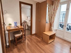 a room with a desk and a table and a bathroom at Hostal Anosa Casa in Santiago de Compostela