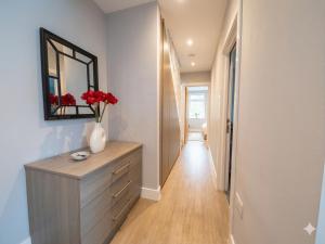 a hallway with a dresser with a mirror and red flowers at Central 3 beds with parking in Reading