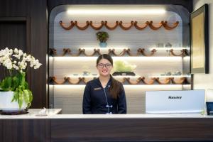 a woman standing behind a counter in a store at Liuli Tile Courtyard Hotel Houhai Tian Anmen Wangfujing in Beijing