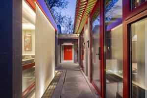 an alley between two buildings with a red door at Liuli Tile Courtyard Hotel Houhai Tian Anmen Wangfujing in Beijing