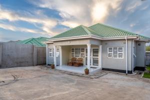 a small white house with a green roof at Timba Lodge in Blantyre