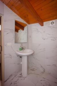 a bathroom with a white sink and marble walls at Bellway Guest House in Shkodër +38 photos