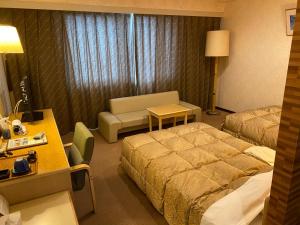 a hotel room with two beds and a desk at Kuji Grand Hotel in Kuji