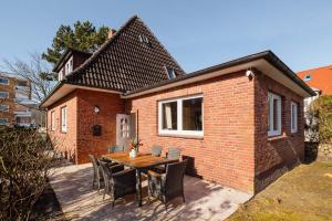 a small brick house with a wooden table and chairs at Ankerplatz Sylt in Sylt