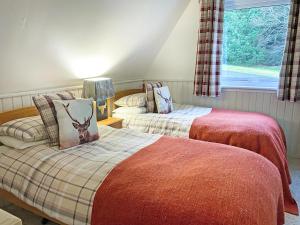 two beds in a room with a window at Glenlivet View in Auchnastank +3 photos