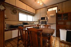 a kitchen with a table and chairs and a refrigerator at The Nomad Inn Yugejima in Kami-yuge