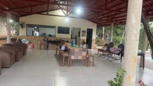 a woman sitting at a table in a living room at Casa do Lago Serra da Mesa - Niquelandia in Niquelândia