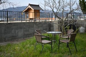 two chairs and a glass table in the grass at The Nomad Inn Yugejima in Kami-yuge