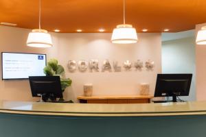 a lobby with a reception desk with two monitors at BLUESEA Coral Beach in Es Cana +41 photos