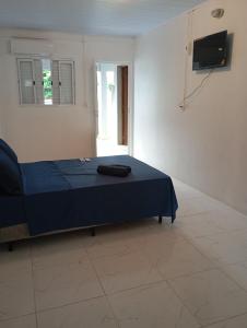 ein Schlafzimmer mit einem blauen Bett und einem Fernseher in der Unterkunft Quarto suíte 2 in Itaqui