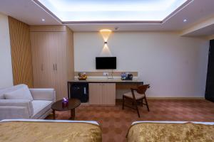a hotel room with a couch and a tv on a wall at Crystal Heritage Inn in Dhaka