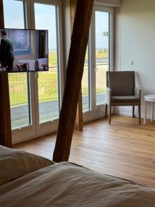 a room with a tv and a chair and windows at Lütt Marschkieker in Langenhorn