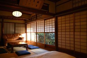 a room with a couch and a table and windows at The Nomad Inn Yugejima in Kami-yuge
