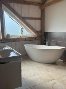 a large white tub in a bathroom with a window at Lütt Marschkieker in Langenhorn +12 photos
