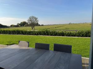 a wooden table with two chairs and a field at Lütt Marschkieker in Langenhorn