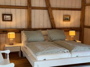 a white bed in a room with wooden walls at Lütt Marschkieker in Langenhorn