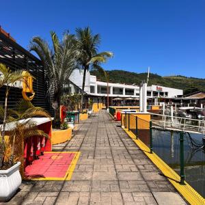 a walkway next to a marina with palm trees and buildings at Angra Sea House in Angra dos Reis