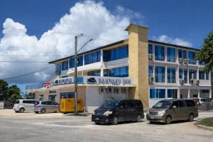Zwei Autos parkten auf einem Parkplatz vor einem Gebäude. in der Unterkunft Fantasy Inn in Nuku‘alofa
