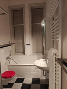 a white bathroom with a red toilet and a sink at Zentrales & gemütliches Zimmer in Lübeck
