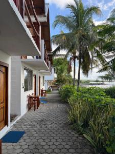 a walkway next to a building with palm trees at Hotel Witttmer in Puerto Velasco Ibarra