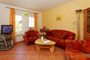 ein Wohnzimmer mit zwei roten Sofas und einem Tisch in der Unterkunft Ferienhaus am Eikboom - DHH2 mit Fasssauna in Ostseebad Karlshagen