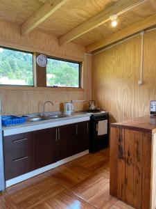 a kitchen with wooden cabinets and a sink and a window at El Tilo Cabin - Hot Tub & Lake Ranco Views in Lago Ranco +19 photos