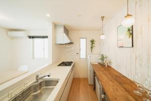 a kitchen with a sink and a wooden counter top at 照間Terumaの美しい海と太陽 Soleが目前に広がる和室ありの宿 TERUSOLEテルソーレ in Uruma +79 photos